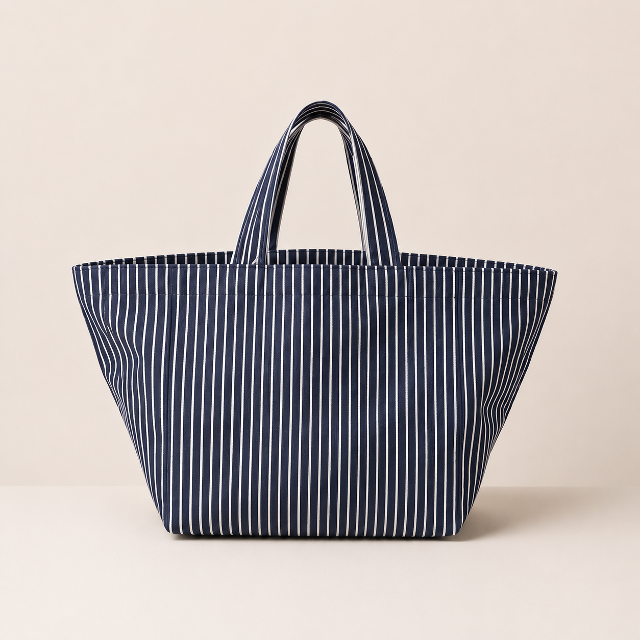Modro bela črtasta tote torba v oversized modelu na nevtralni podlagi.